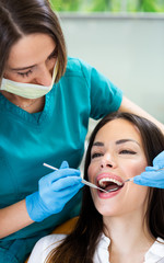 Young woman having dental check up at dentist office, showing perfect straight white teeth.