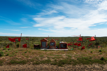 A Guachito Gil shrine with red flags along a road at the Valdes Peninsula in Argentina, South...