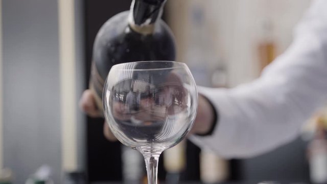 Close up slow motion of a bartender pouring champagne in a tall glass