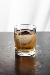 wet glass with whiskey and ice cube on white