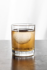 wet glass with strong whiskey and ice cube on white