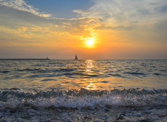 Small yacht in the sea at sunset