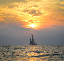 Small yacht in the sea at sunset