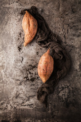 top view of tasty healthy whole sweet potatoes and peeler on grey surface