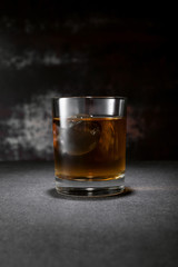 frozen ice cube in glass of whiskey on black with smoke