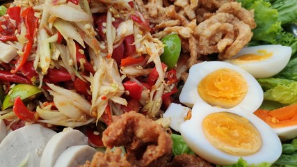 Papaya salad, boiled eggs, fried chicken skin, rice noodles, pork sausage, vegetables background lunch