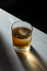 ice cube in glass of strong whiskey isolated on black