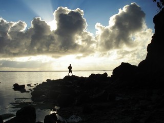 Silhouette of a man standing on rocks with beautiful sunrise clouds