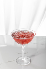 frozen ice cubes in glass with red cocktail on white