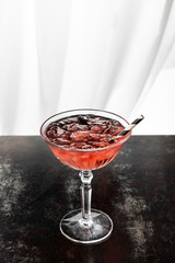 cosmopolitan cocktail with striped straw and ice cubes on white
