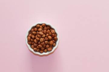 hazelnuts and walnuts in two white cups on a pink background. lots of nuts. the concept of proper...