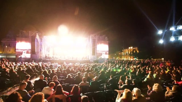 Open-air concert stage at night. People seated on chairs