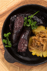 Home-made blood sausage in rustic pan. Sausages cooking in frying pan. Close up of fried sausages in frying pan over wooden background