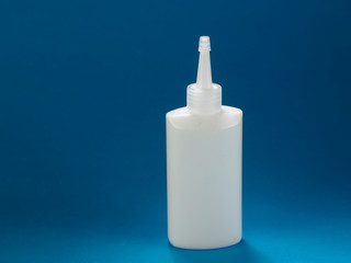 A bottle of white glue on blue craft paper .