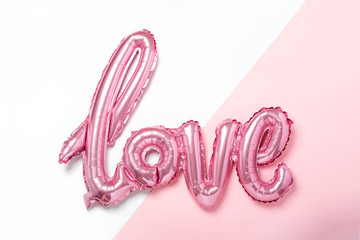 Pink balloons in the form of word Love on pink and white background. Valentines day celebration.
