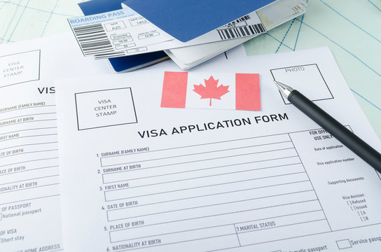 Concept of getting canadian visa. Blank visa application form, pen, passports, tickets and canadian flag on the map