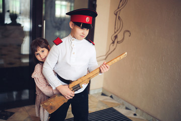 Boy in cadet retro uniform and cap with wooden gun