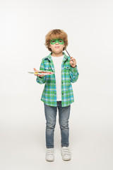 full length view of cute boy with gecko mask painted on face holding palette and paintbrush on white background