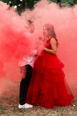 Beautiful romantic couple kiss closeup. Attractive young woman in red dress and crown with handsome man in white shirt are in love on pink smoke. Saint Valentine's Day. Pregnant and wedding concept.