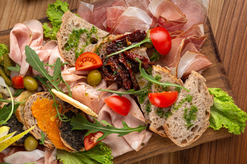 meat and cheese slices with fruits, vegetables, appetizer, prosciutto, sausages. Meat and cheese plate.Traditional italian antipasto, cutting board with salami, cold smoked meat, prosciutto, ham, chee