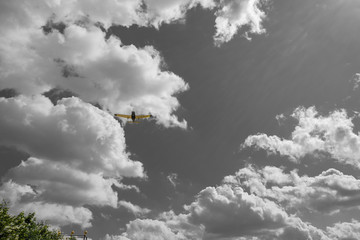 yellow airplane flying over blue sky with white clouds