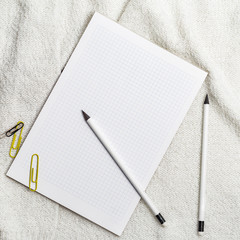 Notatnik i ołówki leżące na białym kocu. Szkicowanie ołówkiem. Robienie notatek.