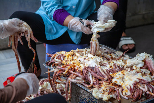 Street sellers seafood, women process squid