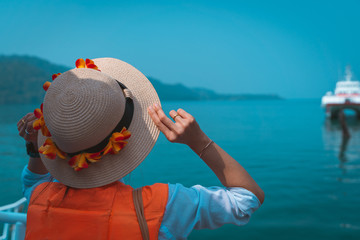 back side view traveler girl wear hat Decorated with flowers stand relax in the sea by wear Life...