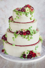 Obraz na płótnie Canvas Festive four-level white elegant cake with cream flowers, wedding cake, cream flowers in the Malaysian technique