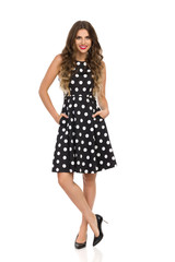 Relaxed Young Woman In Black Cocktail Dress In Polka Dots And High Heels