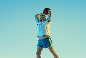 Senior man playing basketball on gradient background in neon light. Caucasian male model in great...