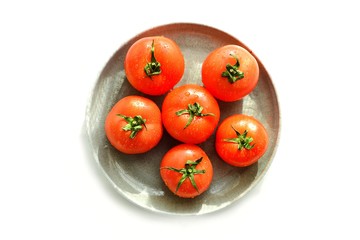 Ripe tomatoes in a gray clay bowl. Whole Tomatoes in a gray plate isolated on white. Top view, place for text.