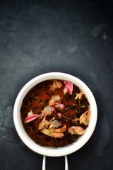 Tea in a white cup on a dark background. Tea with flowers and herbs. Top view of place for text. A cup of tea.