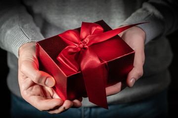 Gift box with red bow in hands. Valentines day concept