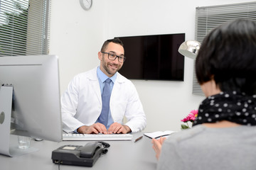 handsome male doctor with a female patient in hospital consultation office desk