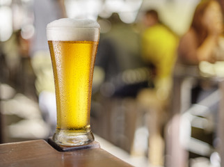 Glass of beer stands on a table in a pub.