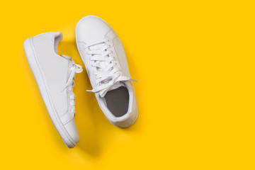 Zapatillas blanca sobre fondo amarillo liso brillante. Vista superior. Copy space