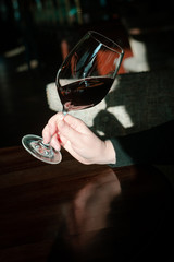 A wine glass of red wine in a women's hand.