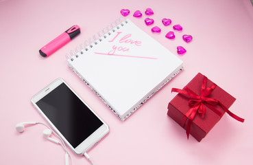 Top view image of an empty laptop, smartphone on a pink background. The concept of love with the desktop heart, Valentine's Day.