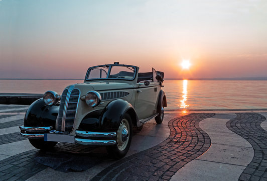 Fototapeta Vintage car near lake at sunset