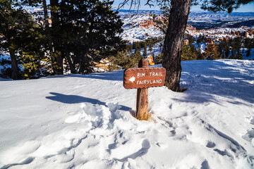 Rim trail & fairyland sign post in Bryce Canyon National Park in Winter covered with snow