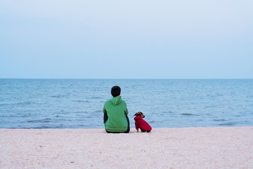 Fototapeta premium Young woman and dog looking to the sea