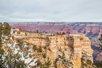 Tourists enjoying a panoramic view of the Grand Canyon along the south rim from the Mather Point on a winter day with snow