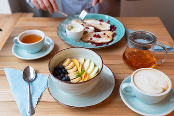 Healthy food for breakfast with hands of men in restaurant. Coffee and tea for drink and plate full of colorful meals in the morning. Breakfast table.