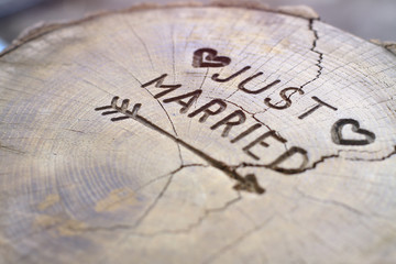 Just married. An inscription on a cut of a tree for a wedding decoration. Handmade decorative board on oak. Photo for your invitation design.