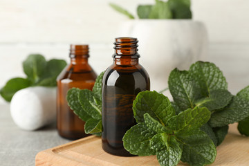 Mortar, medical bottles and mint on grey table, close up