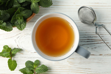 Cup of tea and mint on white wooden table, space for text