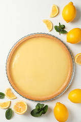 Lemon tart, mint and lemons on white background, top view