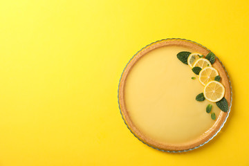 Glass tray with lemon tart on yellow background, top view