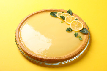 Glass tray with lemon tart on yellow background, close up